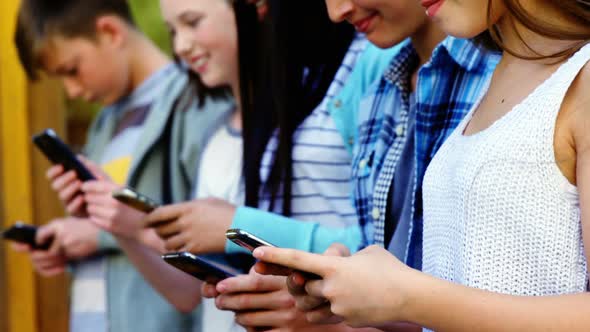 Group of school friends using mobile phone outside school