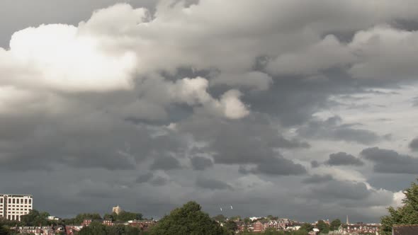 Timelapse of a group of  grey clouds shifting, forming and parting across a suburban landscape, Exet