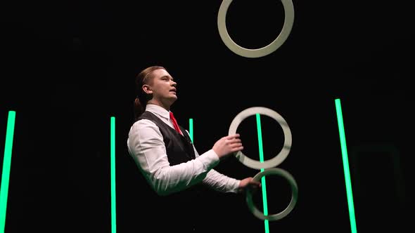 Camera Rotates Around Professional Male Juggler Juggling White Rings