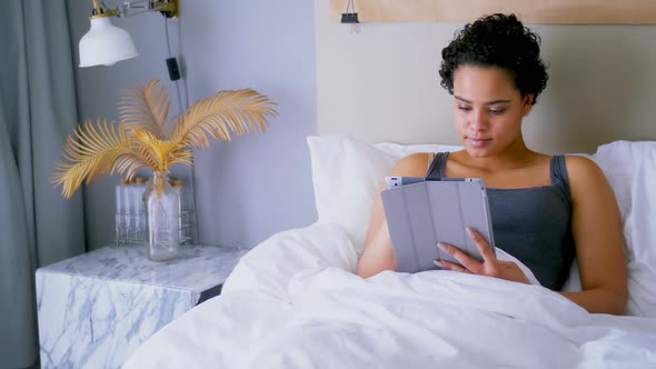 Woman using digital tablet on bed