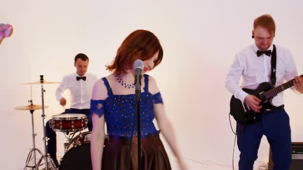 A Musical Band of Four People Playing Song in the Bright Studio - Filming a Music Video - Men