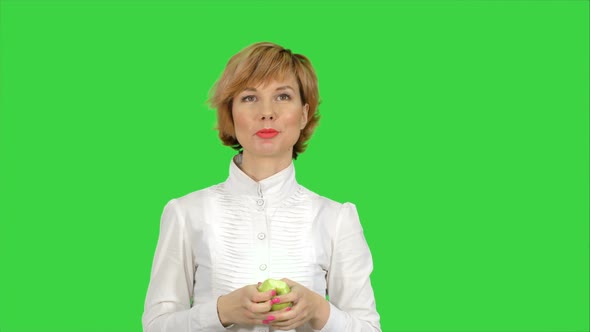 Portrait of Young Woman Eating Green Apple on a Green Screen, Chroma Key