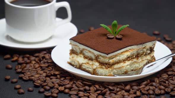 Portion of Traditional Italian Tiramisu dessert, cup of espresso coffee and coffee beans