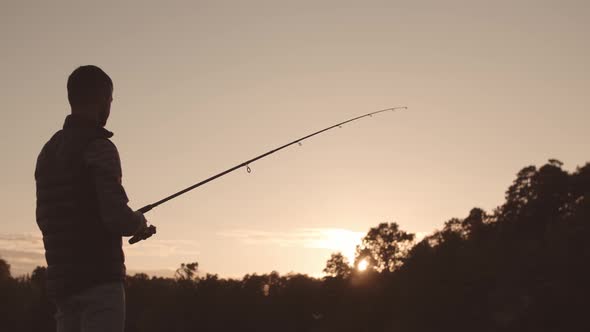 Fisherman with a spinning rod catching fish on a river.