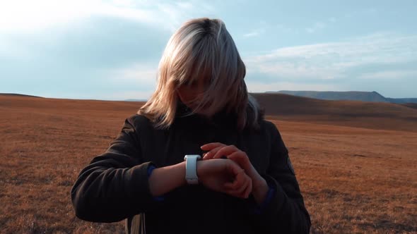 Young Girl Uses a Smart Watch in the Mountains