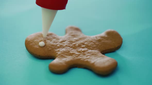 Confectioner is Painting Cookies in the Form of a Ginger Man on the New Year 