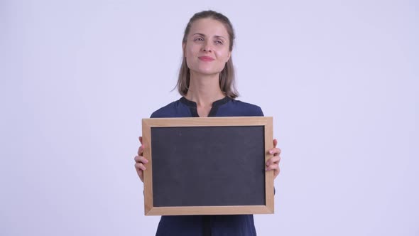 Happy Young Beautiful Businesswoman Thinking While Holding Blackboard