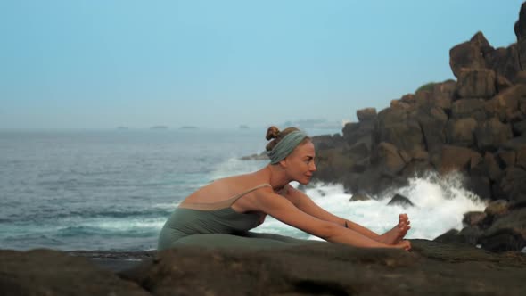 Woman Does Paschimottanasana on Sea Coast Slow Motion