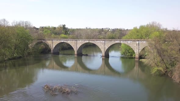 drone flies close to bridge with train tracks.