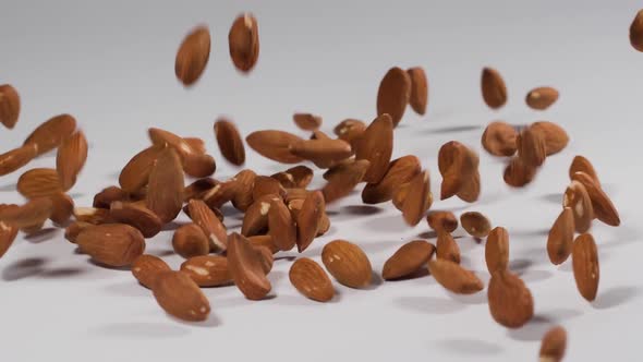 Almonds falling onto a white surface in slow motion