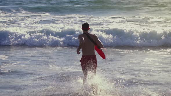 Male lifeguard running along the beach
