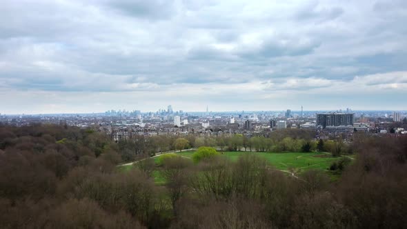 Drone shot flying over Hampstead Heath park with London in backdrop