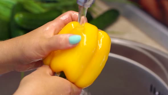 Woman Washing Yellow Pepper in Kitchen. Homemade Food Concept.