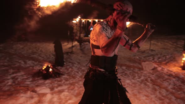 An Evil Aggressive Viking Warrior in Northern Tattoos with a Bare Torso Burning