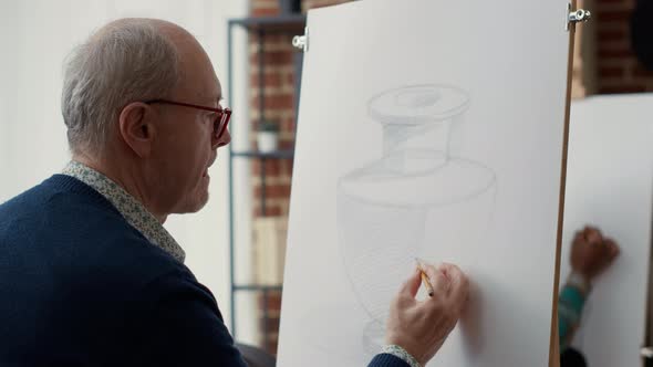 Elder Student Using Pencil to Sketch Vase Model on Paper