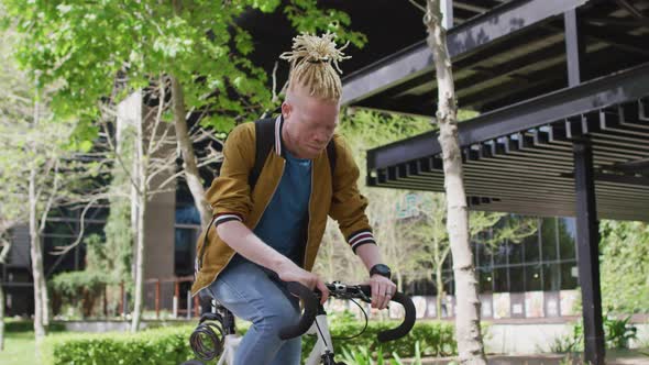 Happy albino african american man with dreadlocks riding bike