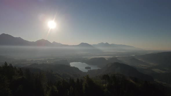 Parallax shot showing Lake Bled in distance during sunset, aerial view