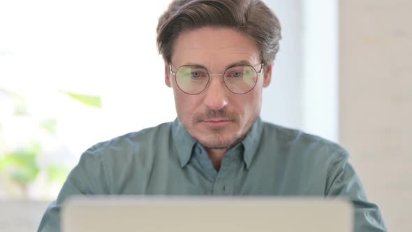 Portrait of Middle Aged Man Working on Laptop