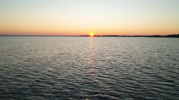 Four Young People are Swimming in Two Green Kayaks in the Direction of the Rising Sun