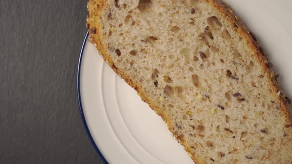 One slice of fresh grain bread on a white plate with a blue border