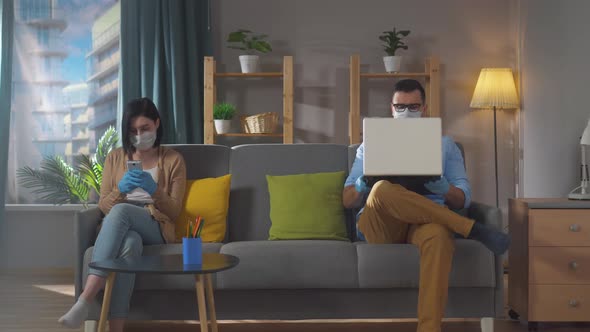 Married Couple with Gadgets in Their Hands are at Home on the Couch Quarantined