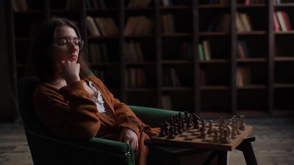 Portrait of Focused Intelligent Female Chess Player Wearing Glasses Making Move in Chess Game