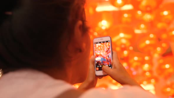 Young Mixed Race Tourist Girl Taking Pictures of Red Chinese Lanterns Using Mobile Phone