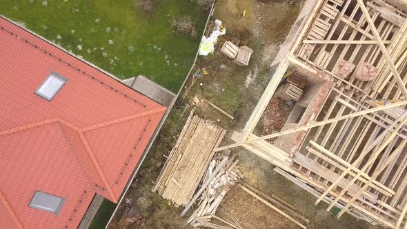 Top Down Aerial View of Two Private Houses One Under Construction with Wooden Roofing Frame and