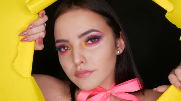 A Beautiful Young Girl Model with a Bright Juicy Yellow Fashion Makeup and a Pink Bow Around Her