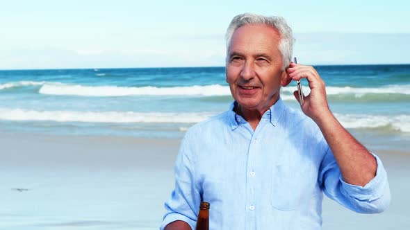 Senior man talking on mobile phone on the phone at the beach