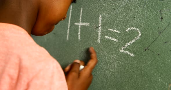 Schoolboy doing mathematics on chalkboard in classroom 4k