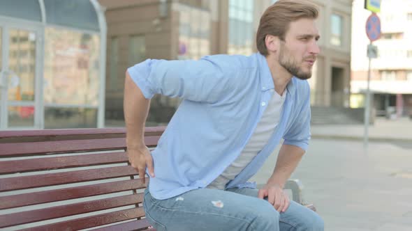 Man Having Back Pain While Sitting on Bench Outdoor