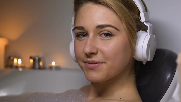 Joyful Woman in Headset Relaxing in Bath With Foam, Smiling Into Camera, Rest