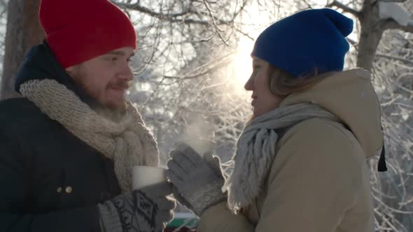 Couple Drinking Hot Tea in Winter Forest