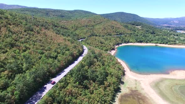 Aerial view of red van driving by artificial lake Peruca, Croatia