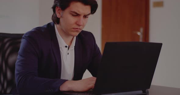Tensed Young Businessman Using Laptop in Office