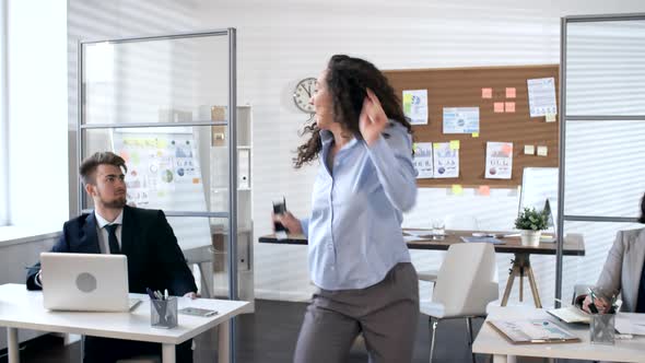 Happy Businesswoman Learning Good News and Dancing in Office