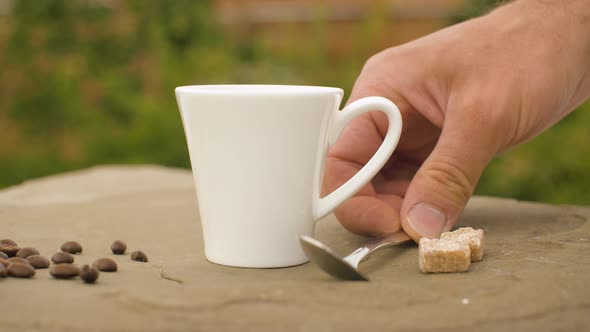 Hand Puts Sugar Into a Cup