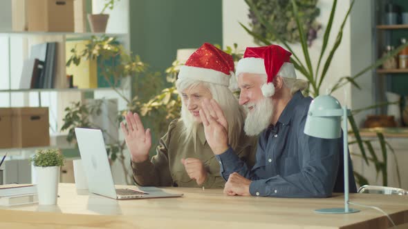 A Happy Elderly Couple in Santa Claus Hats Has Fun Talking Family Video Chat