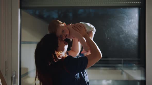 Happy Adult Mom Holding Cute Adorable Infant Child Girl Lifting Up Standing in