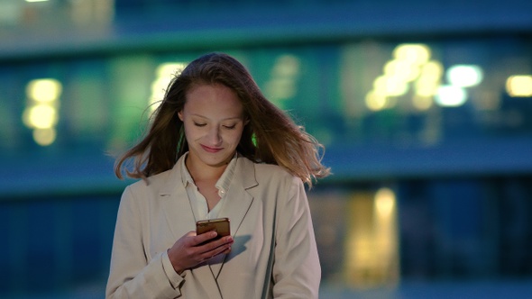 Young girl at night reads message on the smartphone