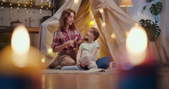 Mother and Daughter in Teepee Tent Combing Hair and Chatting