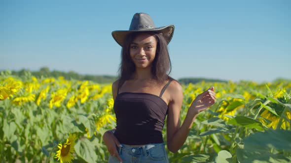 Farmer Woman in Cowboy Hat in Sunflower Field