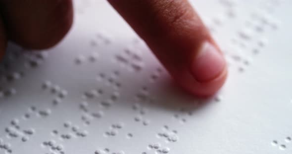 School kid reading a braille book in classroom at school alt