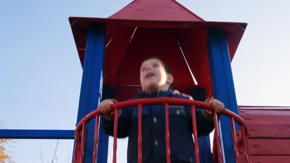 A Child Jumps on the Balcony of the Castle on the Playground Against the Sky