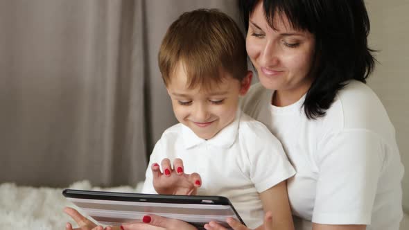 A Happy Mother and Son Watch the Film with a Tablet