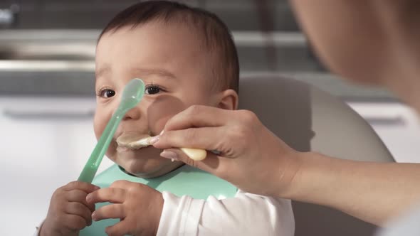 Sloppy 1-Year-Old Asian Baby Being Fed Puree