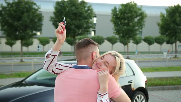 Woman Hugs Man with Her Hands and Holds Car Keys