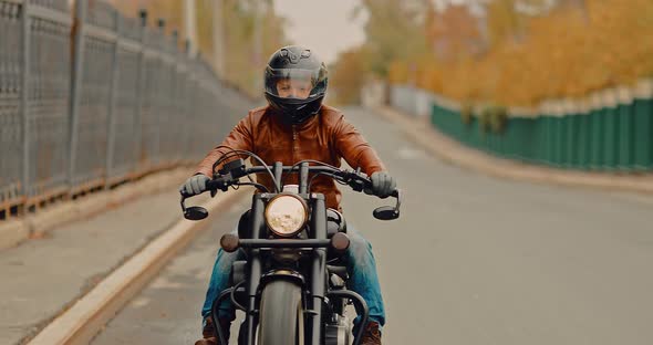 Cool Biker Rides a Helmet Through the Streets of the City in the Fall