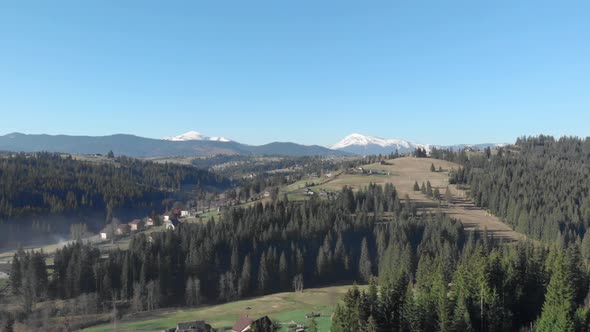 Mountains landscape with snowy peaks, blue sky and green trees